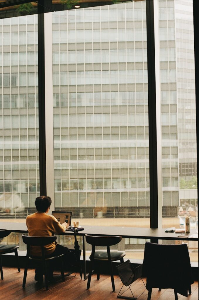Person works at a desk overlooking tall buildings.